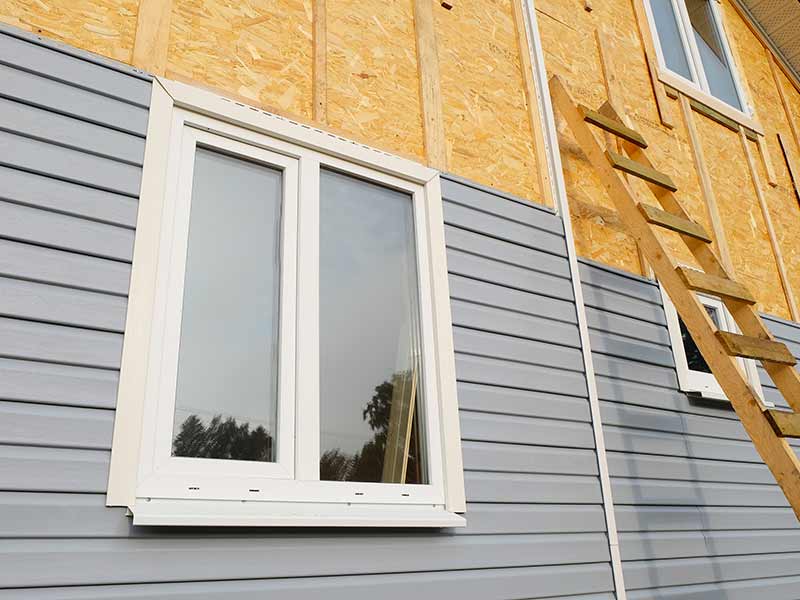 Close up of new gray siding being installed on the side of a home